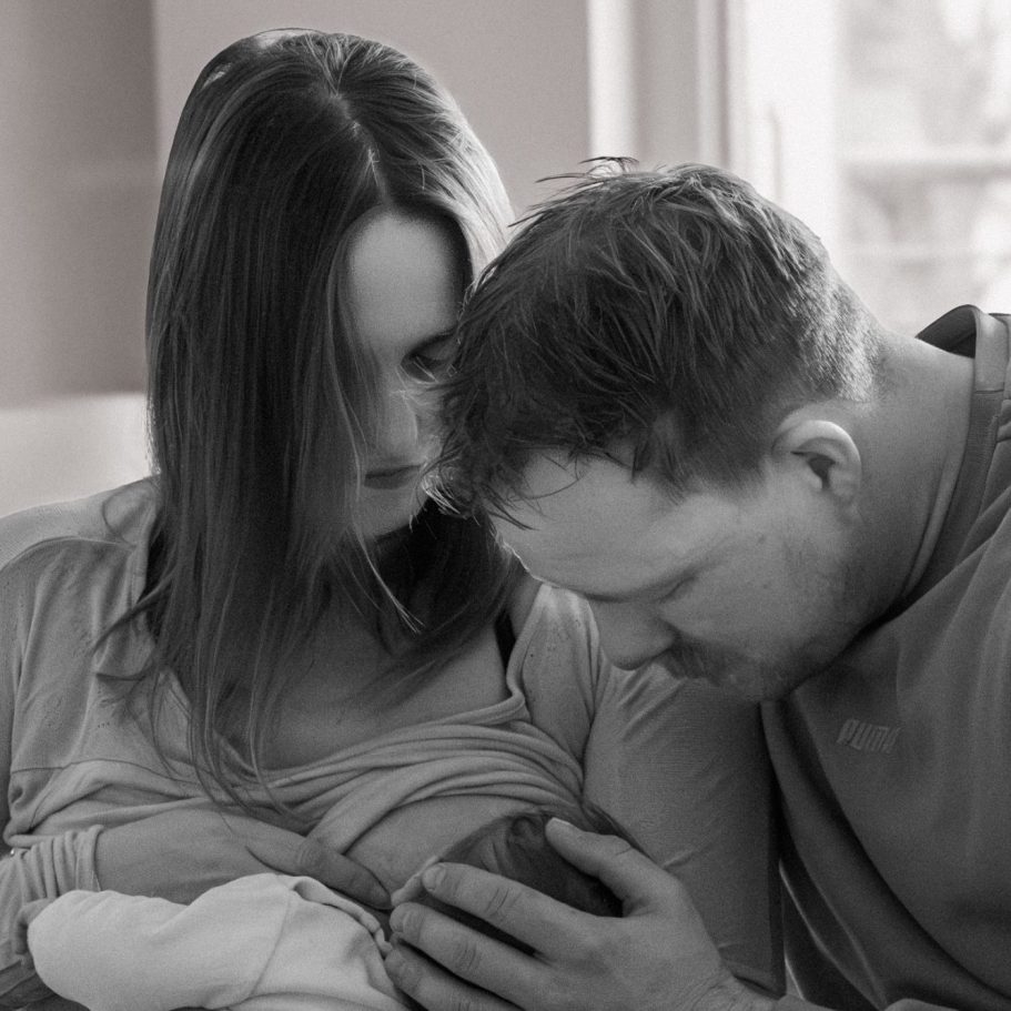 Ein Elternpaar betrachtet liebevoll ihr neugeborenes Baby.