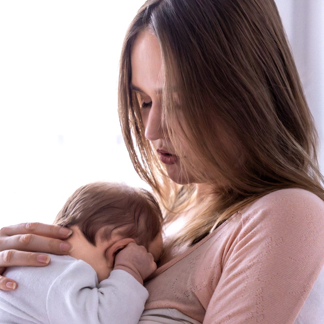 Eine Mutter hält ihr schlafendes Baby an der Brust.