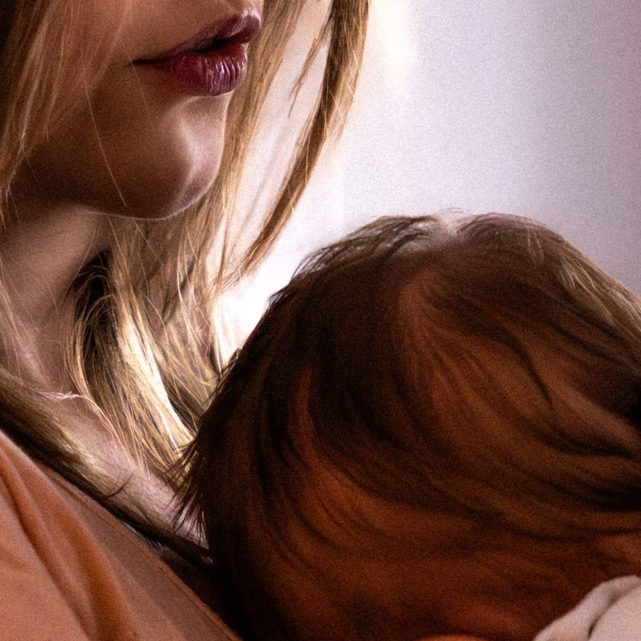 Eine Frau hält ein Baby in ihren Armen, das eng an sie gekuschelt ist. Newborn Fotografie Berlin.