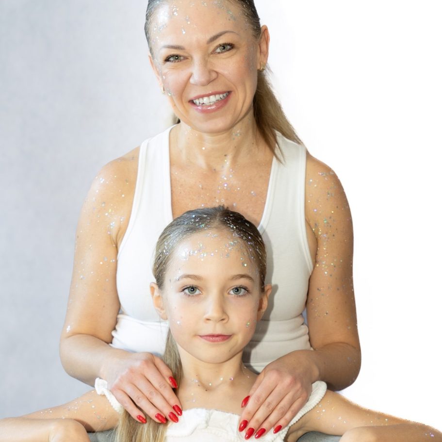 Eine lächelnde Frau sitzt hinter einem Mädchen, beide tragen helle Kleidung. Fotoshooting Indoor Berlin.