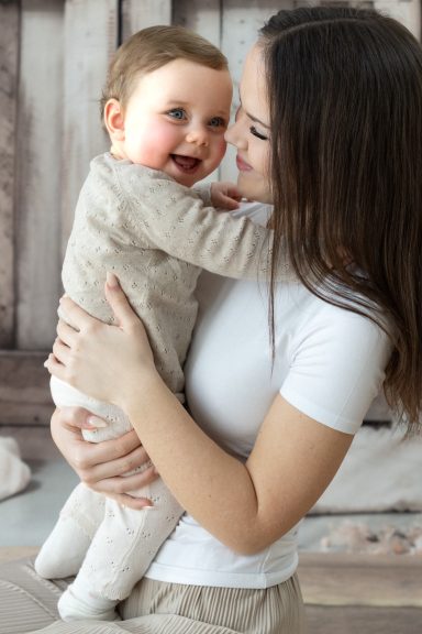 Schwester umarmt Baby bei Familienfotoshooting