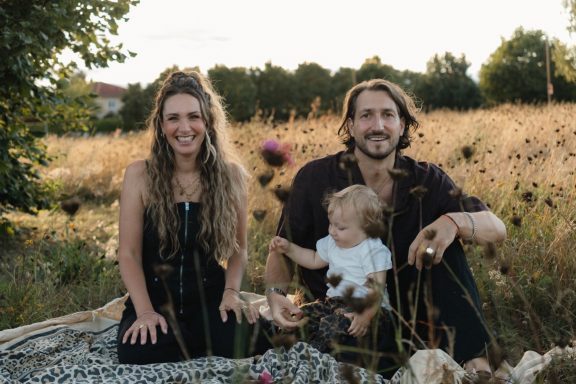 Familie mit Baby im Gas sitzend beim Fotoshooting am Wuhlewanderweg in Berlin-Biesdorf