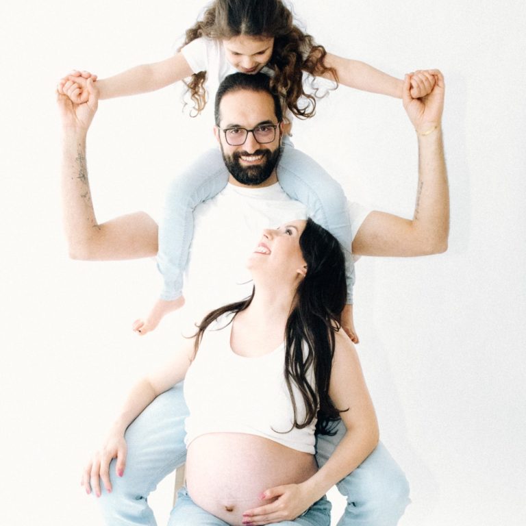 Babybauch Fotoshooting Berlin Lachende Familie - Mama hält sich den Babybauch